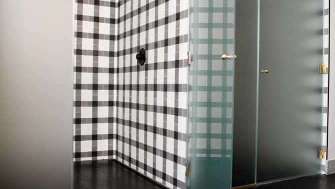 Two spacious showers with black and white tile and frosted glass doors.