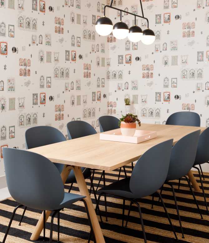 Room with patterned wall paper and striped floor, with table and several chairs.