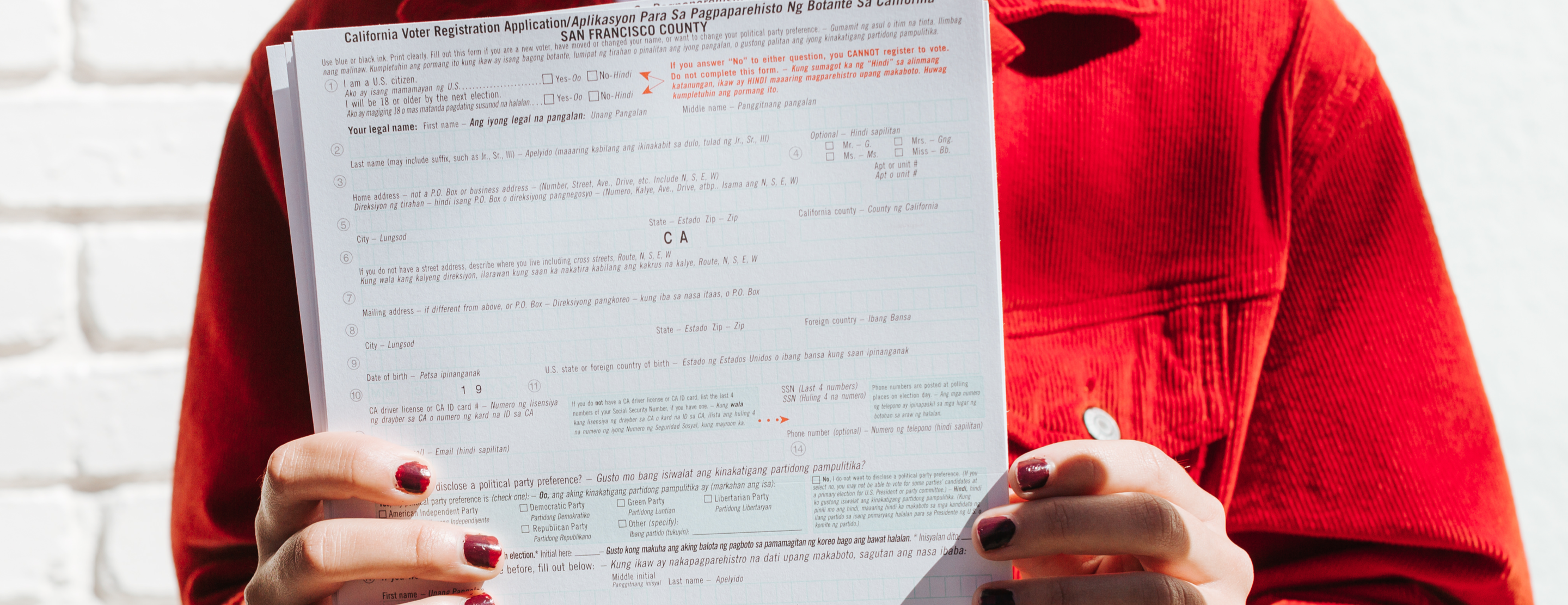 Close up of voter registration form held by person wearing red